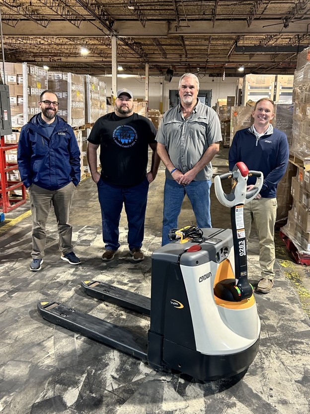 Bailey Equipment and Intralogistics workers behind a Crown electric pallet jack