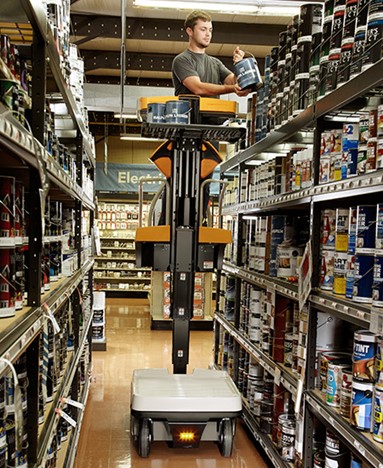 Man using a motorized lift to reach and handle paint cans