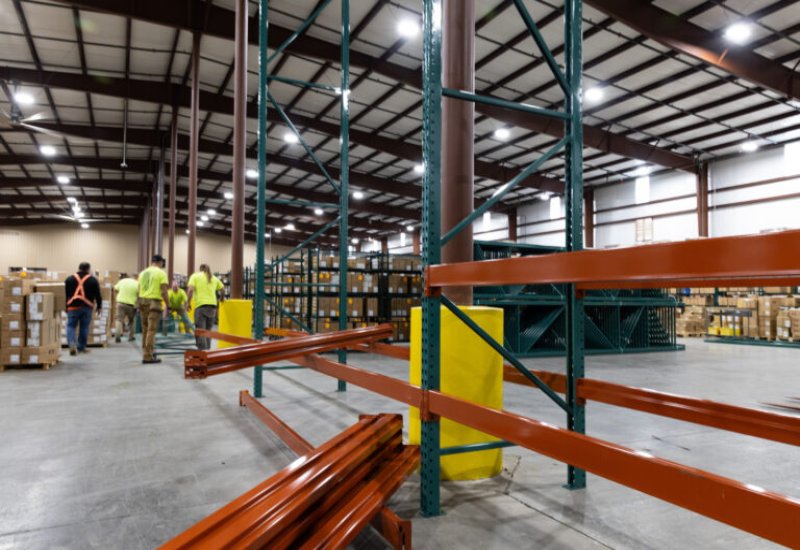 Warehouse workers assembling heavy-duty metal shelving and racks among stacked boxes in Tennessee and Kentucky